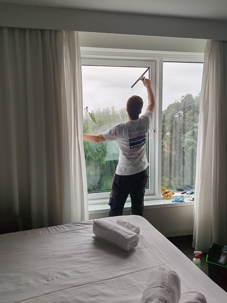 Operario de Limpatex limpiando con haragán el ventanal de una habitación de hotel